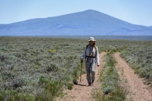 hiker walking across the sagebrush steppe in "the land between"