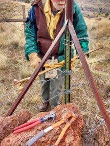 A volunteer works to retrofit barbed wire fence